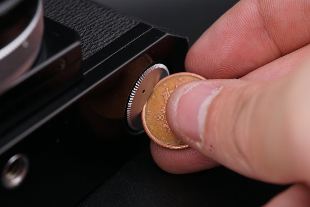 opening a Canon F-1 battery compartment with a coin