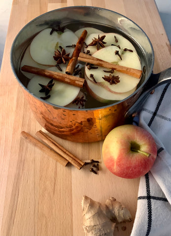 Fall Simmer Pot with apples, cinnamon sticks, ginger, cloves and water. A copper pot is filled with simmer pot ingredients.