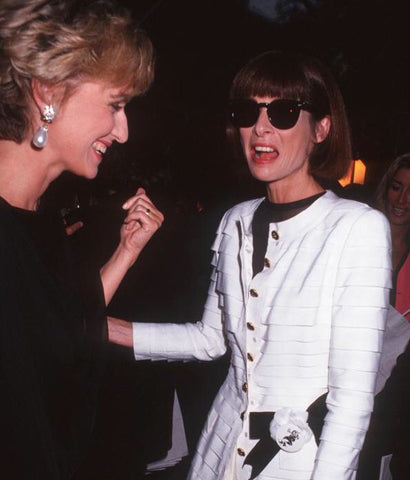 Anna Wintour wearing black round frame sunglasses and white blazer dress