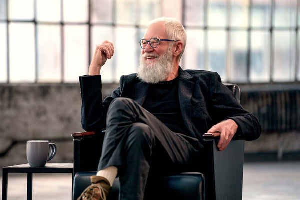 David-Letterman-in-studio-chair-wearing-round-blue-eyeglasses-frame-smiling