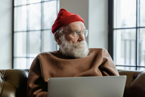 Elderly man with red hat and round optical glasses