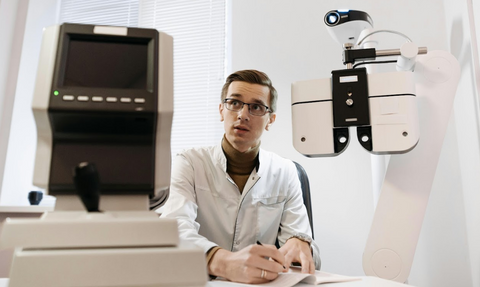 trained optician with glasses going through an eye examination with patient