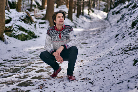 Muž v podřepu v zimní krajině v zimních barefoot botách
