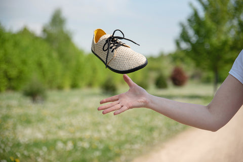 Žena vyhazuje do vzduchu jutové barefoot tenisky Ahinsa shoes.