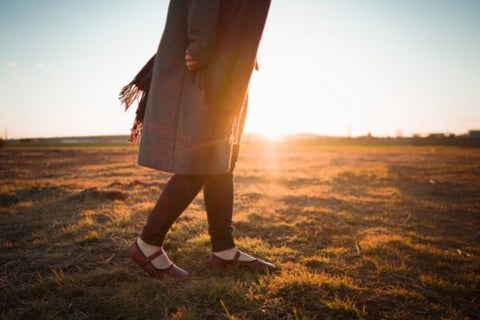 Žena kráčí po louce v barefoot balerínkách Ahinsa shoes. 