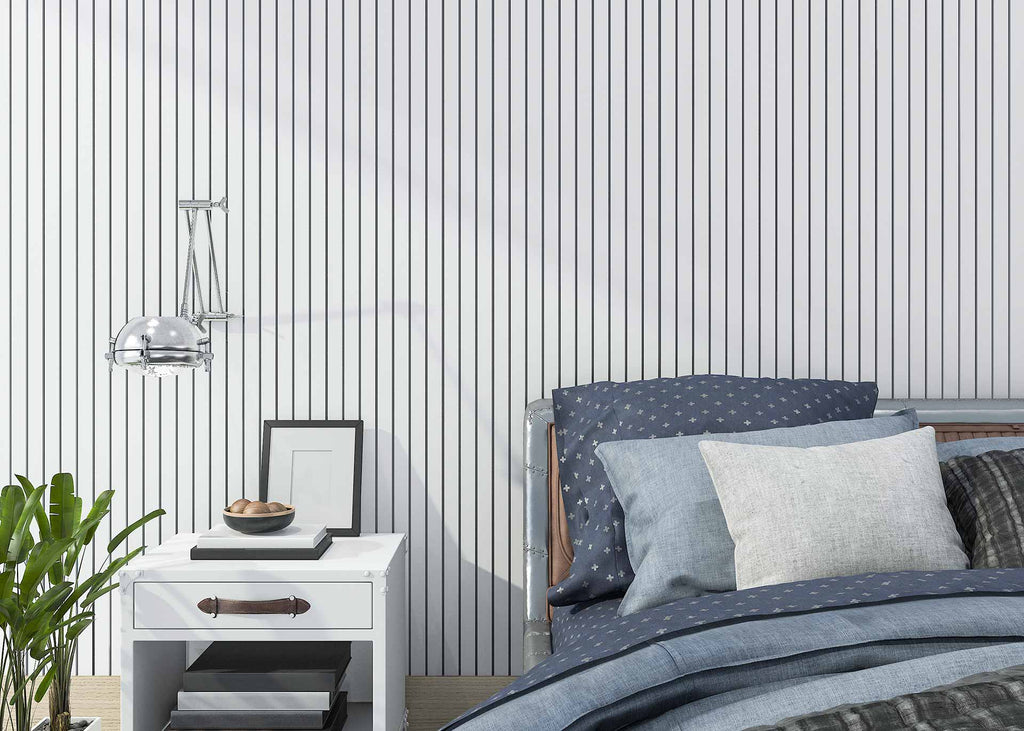 room with striped wallpaper, bed with blue sheets and pillows, and white small table