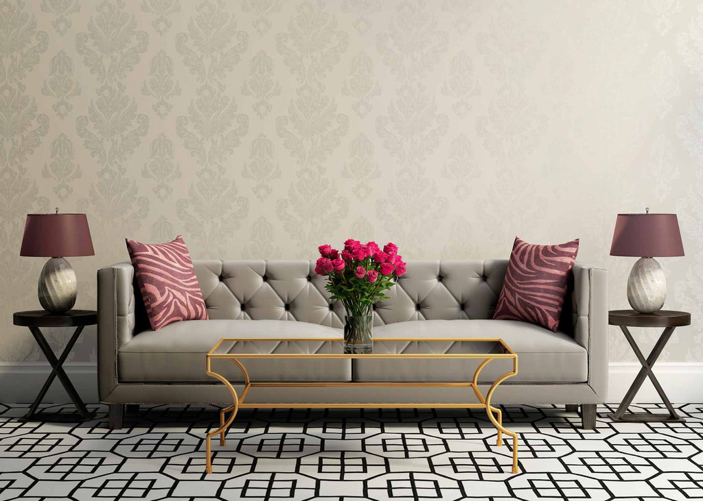room with ornate patterned beige wallpaper, beige long couch, and table with flowers