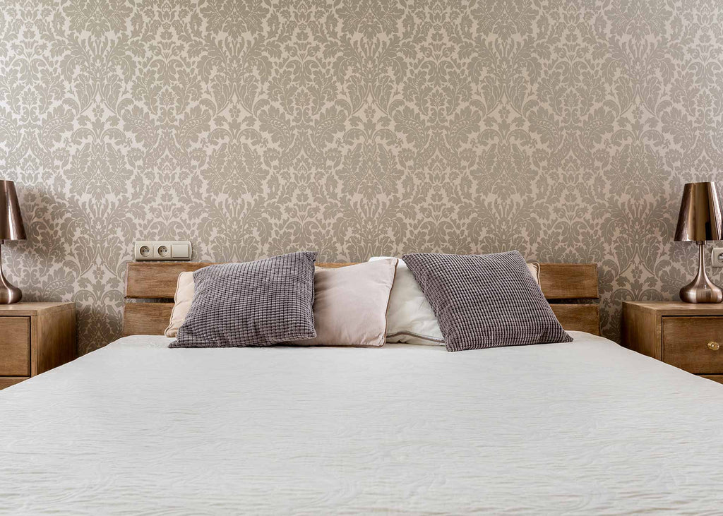 room with ornate wallpaper and bed with pillows and sheets with muted colours