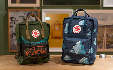Two Fjällräven Kånken backpacks with custom outdoor paintings on display, showcasing the brand's iconic design.