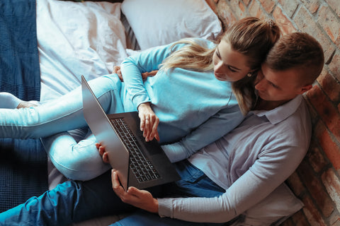 a couple sits together while doing a virtual class together