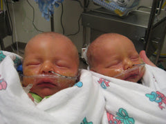 two preemie babies with breathing tubes