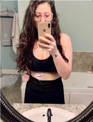 woman taking mirror selfie with diabetes device visible and wearing insulin pump belt