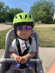 toddler lily with green helmet sitting in bike seat