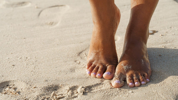 Füße im Sand mit Zehen Nägeln in Flieder