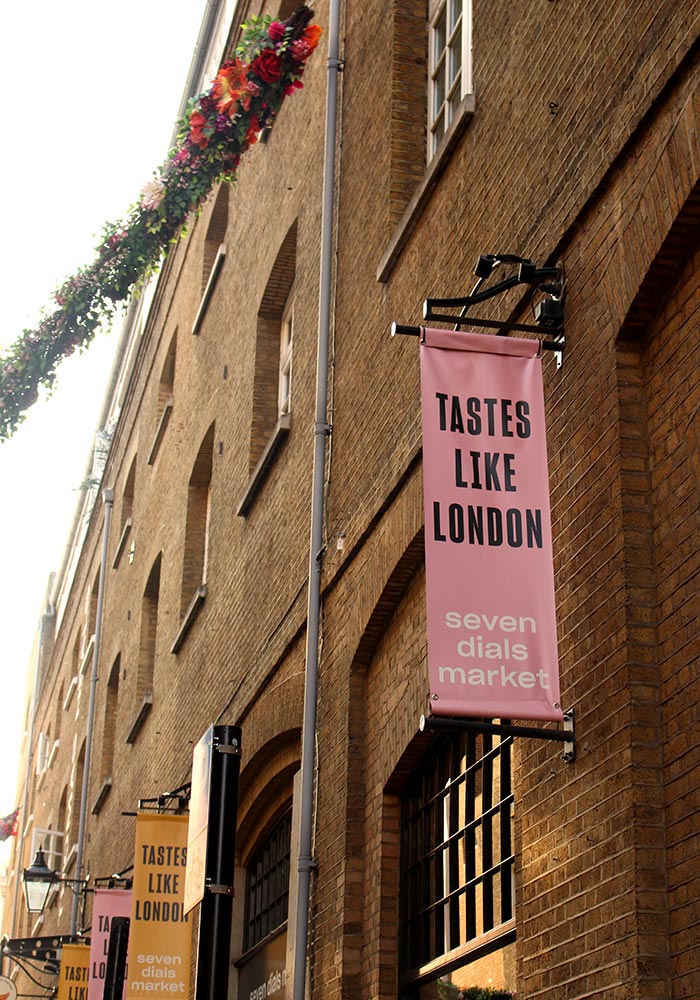 Image of Seven Dials Market building with a pink 'Tastes Like London' banner hanging from the building