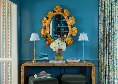 Elliston House's Dover Pool pattern on custom fabric lampshades on buffet lamps sitting atop a burl wood console table with a backdrop of Farrow and Ball's Stone Blue walls in high gloss.