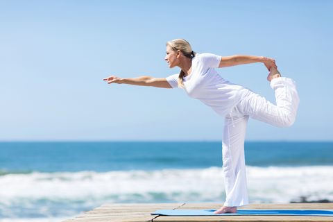 Yoga gyakorlat a tengerparton, amelyet egy középkorú nő végez