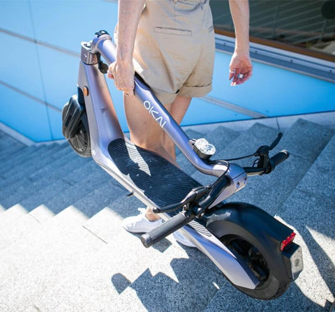 Man on stairs transports folding electric scooter