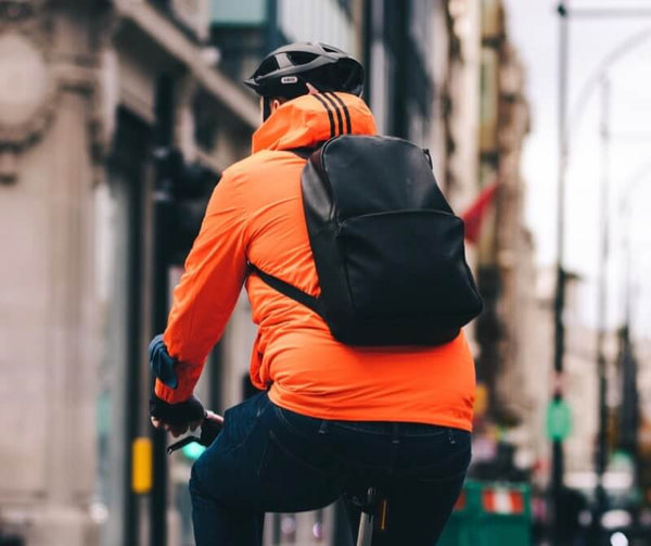 Man on bicycle wears reflective orange jacket