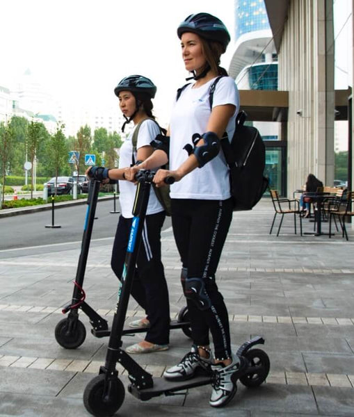 Two women on electric scooter wears helmet