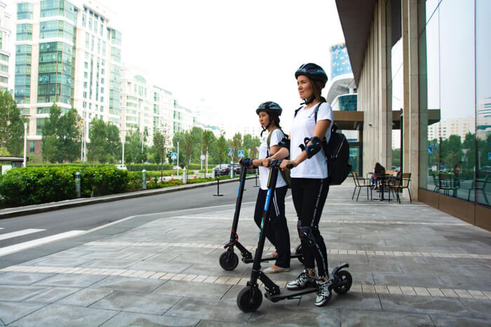 Two women with helmet on electric scooters