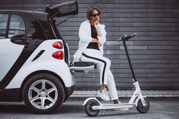 jeune femme assise dans une voiture avec un scooter électrique