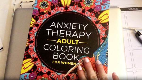 A woman is about to open the Anxiety Therapy Adult Coloring book