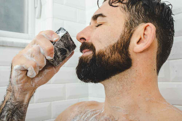 A man smells his Dr. Squatch soap bar while in the shower