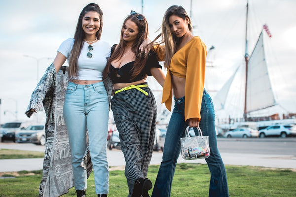 A group of three girls pose in front of ships at the San Diego harbor