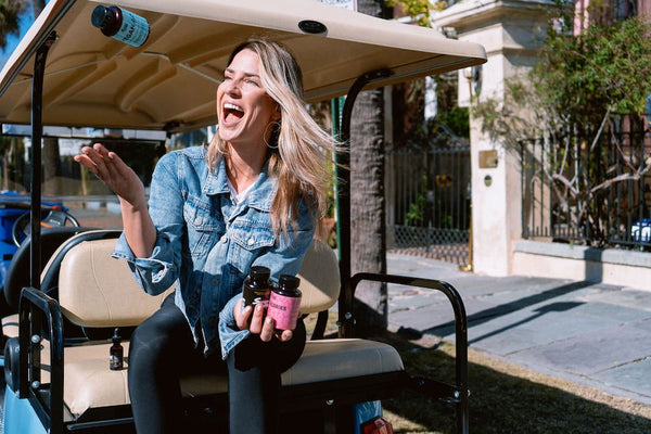 A happy girl holds Sunday Scaries products in her hands while hanging out on the back of a golf cart