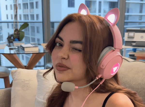 A girl plays video games while wearing her pink, cat ear headset