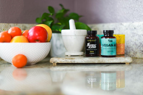 A bowl of fruit on a kitchen counter top next to Sunday Scaries products