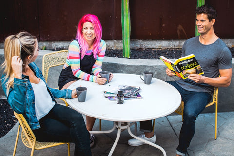 Two girls and one guy socialize around a round table