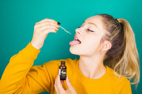 A young woman drops some Sunday Scaries CBD Oil on her tongue