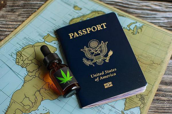 A bottle of CBD oil lays next to a passport representing the international rules for traveling with CBD