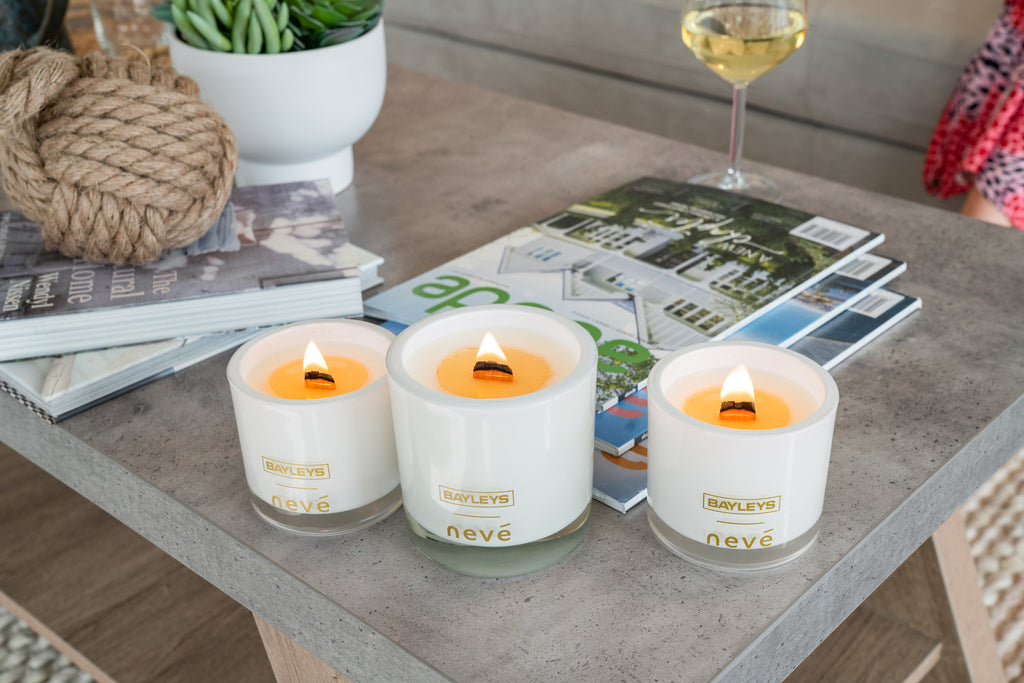 Three candles burning on a coffee table with magazines and a glass of wine