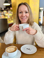 Kundenmeeting: Frau im Café, welche eine Kaffeetasse in der Hand hält