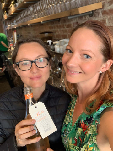 Owner and Guide Jess Hopwood pictured with Pascaline Lepeltier with a bottle of ancestral method Gamay from Bella Wines in Naramata - Farm to Glass Wine Tours