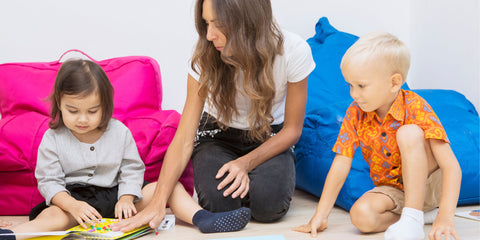 Speech pathologist sitting with a young boy and girl pointing to an activity