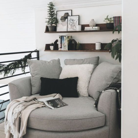 Floating bookshelves behind gray chair in reading nook