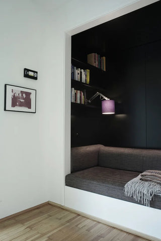 Closet turned into dark reading nook with cushions and book shelf