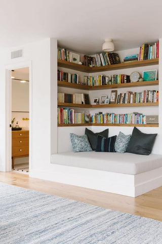 Corner reading nook with book shelves and cushioned seating area
