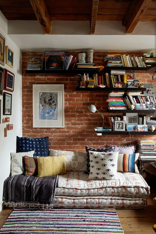 Reading nook with rug, cushions, and shelving on a brick wall