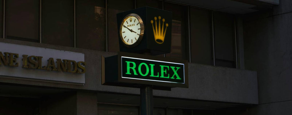 A brightly lit storefront with a Rolex logo and banner advertising the Submariner timepiece.