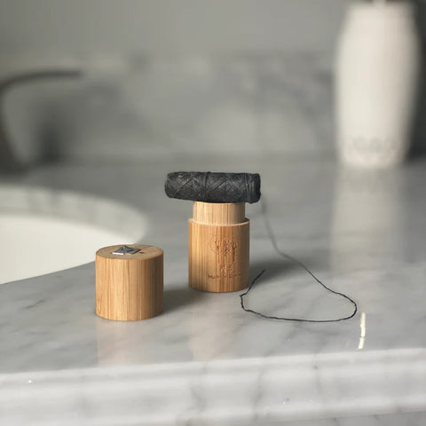 bamboo floss container and charcoal infused biodegradable floss on a counter