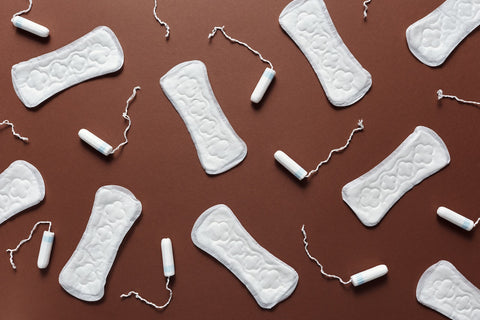 18 disposable pads and tampons on a brown background represent the average number used per period.