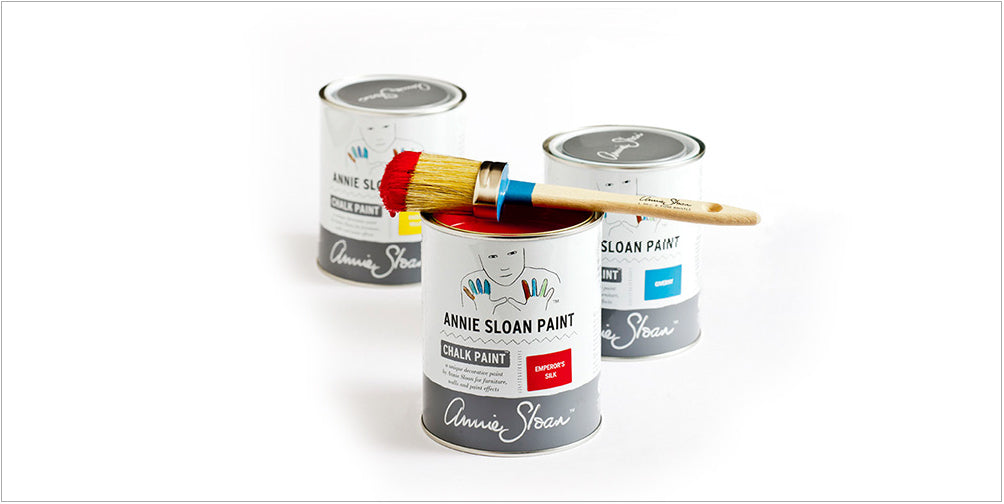 Three tins of chalk paint with a paint brush on top