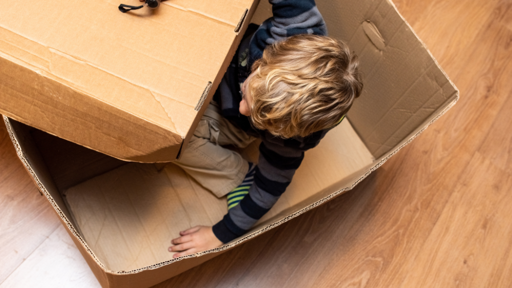 Top view of a kid inside a huge box while the lid is open