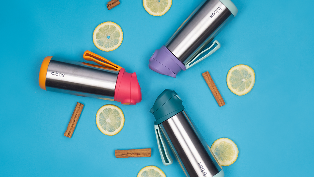 Insulated Sport Spout Bottles in circle surrounded by rounded slices of lemon and cinnamon sticks