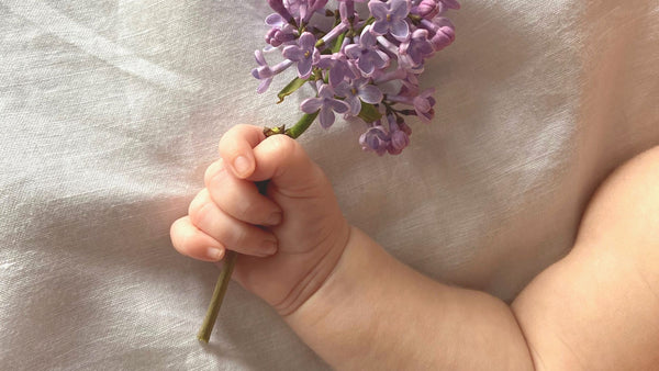 baby holding flowers in spring